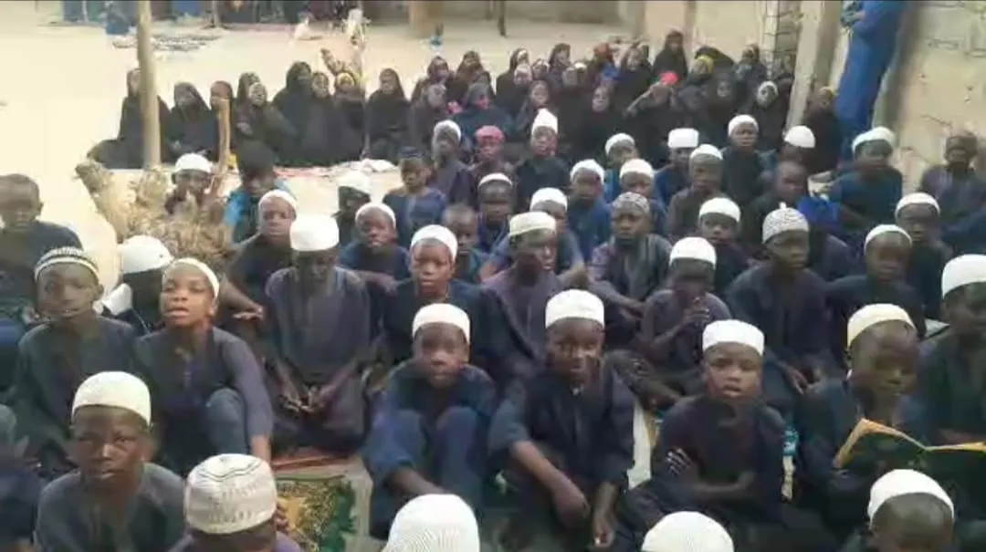 Rows of young students in white caps seated together for a Qur'an lesson.